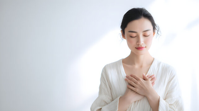 胸に手を添え目を閉じて心を整える女性の心の安定。癒しを表現したポートレート