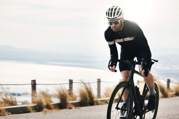 Naklejka premium Fitness, cycling or person on road with bike, endurance training or challenge in cardio workout. Serious, space or cyclist outdoor with bicycle, physical activity or riding practice in sports hobby.