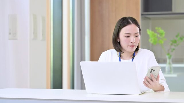 パソコンを前に忙しくてスマホを見たり悩む考える困るオフィスカジュアルの女性、繁忙期や忙しいビジネスイメージ動画