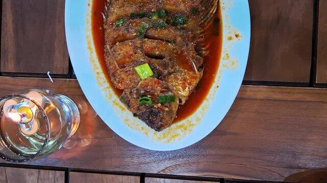 Indonesian sweet and sour gourami fish served with crispy fried gurame and rich sweet sour sauce, topped with fresh vegetables and spices. Traditional Asian seafood cuisine popular in Indonesian.
