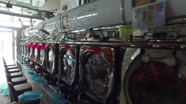 Tracking shot of empty Pachinko machines in a Japanese gaming parlor.
