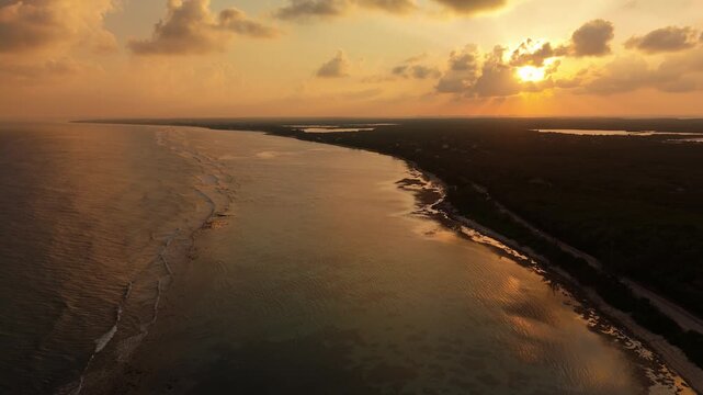 Drone ascends and pulls back over sunset-lit water near Bodden Town on Grand Cayman&rsquo;s coast