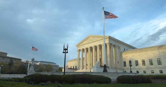 US Supreme Court Building in Fading Afternoon Light and American Flag Waving Above