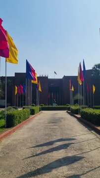 Vertical shot of the entrance of the Shilpacharya Zainul Folk and Craft Museum in Sonargaon, Bangladesh with colorful flags swaying in the wind on a clear sunny day at this cultural landmark
