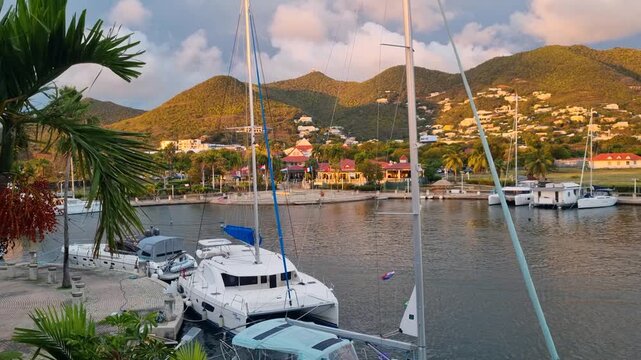 View over Simpson Bay, Sint Maarten, with anchored catamarans and a hilly coastline glowing in warm golden-hour light under a clear, sunny sky, capturing a calm Caribbean evening atmosphere
