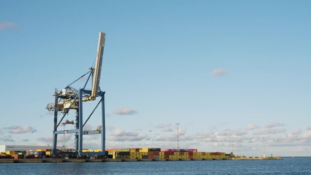 Industrial container crane and colorful shipping containers at commercial port, logistics and trade