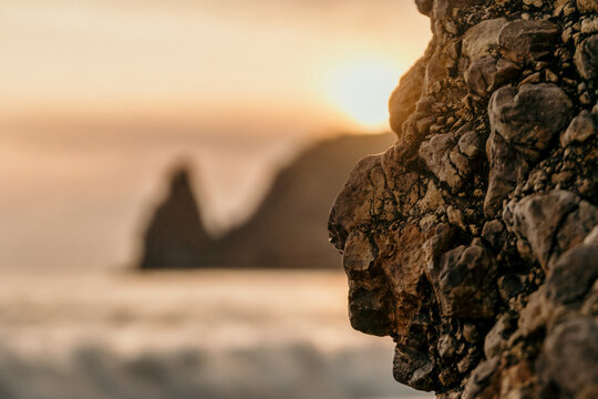 Rock texture sunset close up of a rugged stone cliff face with a blurred coastal background at golden hour