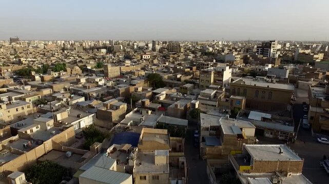 Sweeping high angle view shows intricate tile patterns on shrine dome surrounded by bustling rooftops and narrow bazaar streets in ancient Qom city under bright midday sun Iran stock video