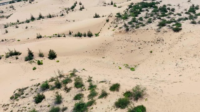 Aerial drone footage of the coastal sand dunes located between Hon Kho and Eo Gio, Quy Nhon, Binh Dinh Province, Vietnam. The drone glides low over rolling sandy dunes dotted with sparse scrubby coast