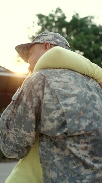 Happy wife hugging American soldier husband returning home after war. Emotional family reunion, peace, freedom, patriotism and hopeful post war recovery concept.
