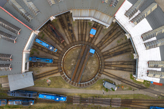 Aerial view of a railway roundhouse with a central turntable and blue locomotives parked on radial tracks in Breclav, South Moravian Region, Czechia.