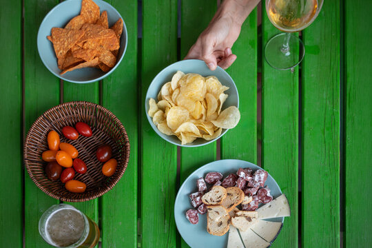 Top view of snack bowls and wine on green wooden table