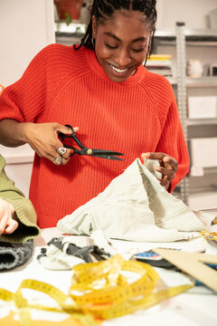 Seamstress cutting fabric at fashion atelier workspace