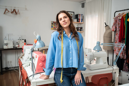 Fashion designer in atelier with sewing machine and dress form