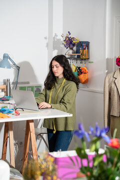 Woman designer working on laptop in fashion atelier studio