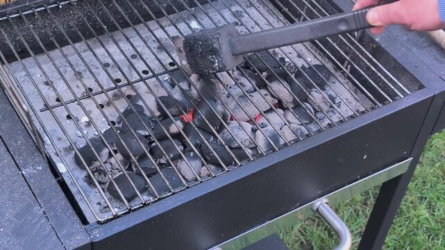 Grilling activity cleaning the grill grate while heating up from the coals
