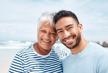 Fototapeta premium Happy, portrait and man with senior mother at beach for summer holiday, weekend trip and bonding. Love, son and elderly mom with connection at seaside for vacation smile, retirement support or travel