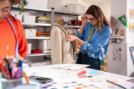 Woman measuring and fitting jacket in atelier