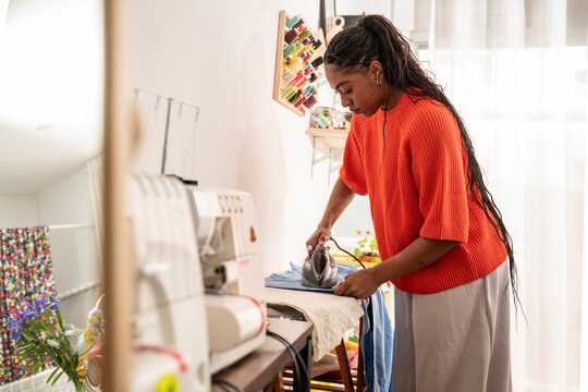 Black colombian woman pressing fabric at fashion atelier sewing studio