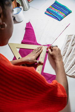 Woman measuring fabric pattern at a fashion atelier desk