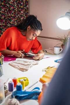Black colombian woman cutting fabric at fashion atelier worktable