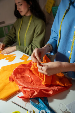 Multiethnic women sewing garment pieces in atelier studio