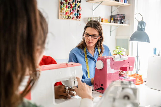 Woman sewing at fashion atelier with machine and fabric
