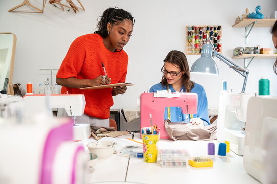 Sewing teacher guiding student at modern workshop class