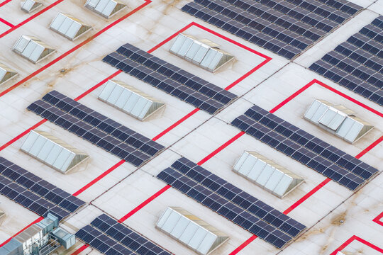 Aerial view of solar panels and skylights on an industrial roof with red geometric markings in Breclav, South Moravian Region, Czechia.
