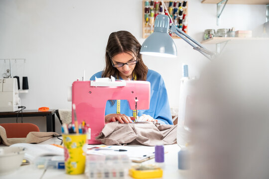 Woman sewing garment at fashion atelier with pink machine