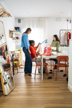 Multiethnic women sewing in bright fashion atelier studio