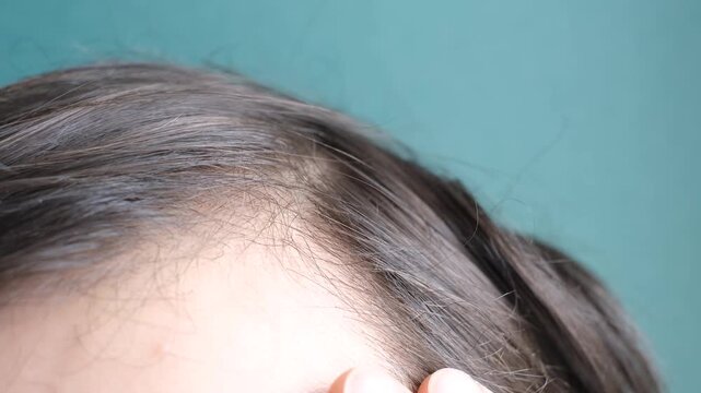 Man touching her hair close-up on mint background, hair loss concept.