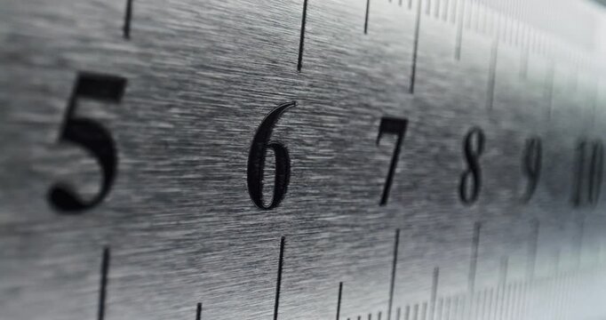 Slow Pan Over Metal Ruler. Smooth slow movement across extreme close-up of metallic ruler with black numbers and brushed surface.