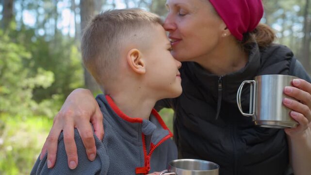 Loving mother kissing her son during camping break. This tender moment shows emotional support and strong family bond which is essential for child mental health.