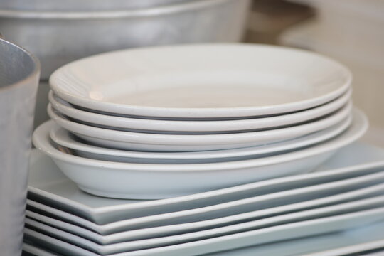 Stack of Clean White Ceramic Plates and Platters in a Professional Kitchen