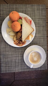 Healthy breakfast plate with toast beans and fresh fruit. Top view of a morning meal consisting of white bread, potatoes, beans, cucumbers, and oranges on a table mat