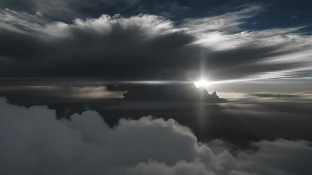 Epic cloudscape aerial view from airplane cabin with sunburst breaking through massive storm clouds and layers of fog