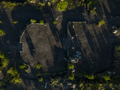 Aerial view of Bunker Kaliadem Merapi surrounded by volcanic soil and sparse greenery with long shadows at sunset Kecamatan Pakem, Daerah Istimewa Yogya, Indonesia.