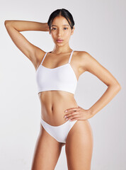 Obraz premium Portrait, self care and woman with healthy body, serious and skincare glow with cosmetics in studio. White background, confident and person in underwear, lose weight and wellness goals in Brazil