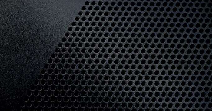 Perforated Metal Surface. A black perforated surface with a repeating pattern of holes creates a textured, industrial look.
