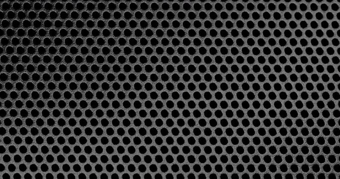 Perforated Metal Surface. A black perforated surface with a repeating pattern of holes creates a textured, industrial look.