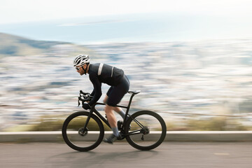 Fitness, bike or cyclist outdoor with motion blur, endurance training or speed in cardio workout. Fast, space or male person on road with bicycle, physical activity or riding practice in sport hobby. © peopleimages.com