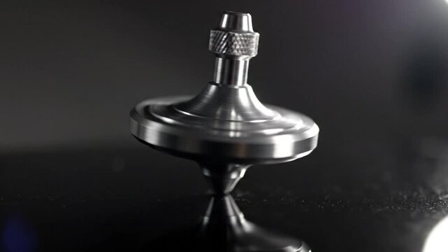 Metal spinning top spinning on reflective surface with cinematic lighting and focus on movement and reflection