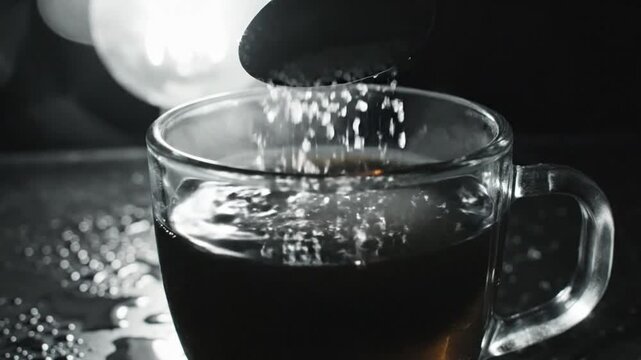 Adding granular sugar to a cup of hot tea: a close-up shot of the sweetening process with steam rising.