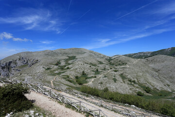 Fototapeta premium Winding Hiking Path with Wooden Fence on the Rocky Slopes of Mount Redentore