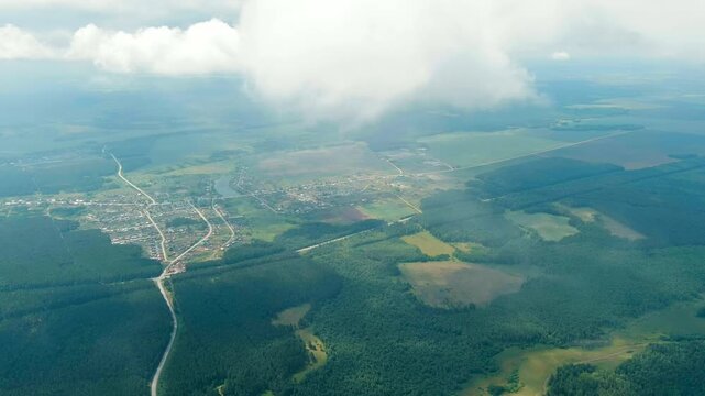Russia, Ural. Flight over woodland, fields road. Shadows from the clouds. Flying through the clouds. Drone footage