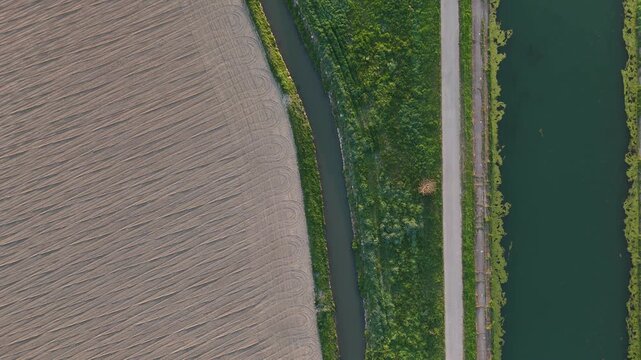 Idrovia Milano Cremona canal near nearTop down drone o Porto Canale Cremona Lombardy Italy with parallel irrigation channel, service road and plowed farmland textures in Po Valley, top down drone shot