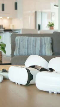 Vertical video: Panning camera showing two VR headsets and controller on table, revealing kitchen