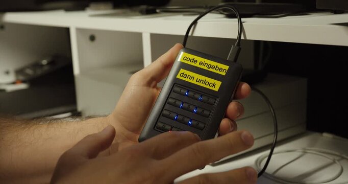 Close-up of a person entering a code on a keypad external hard drive to unlock secure data storage.