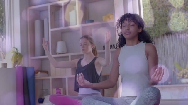 2 teens closing eyes holding mudra doing yoga for calm bokeh drifting over them, camera panning